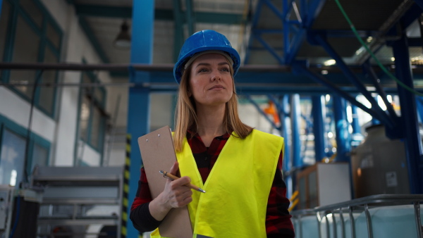 Portrait of female engineer working in industrial factory, doing control.