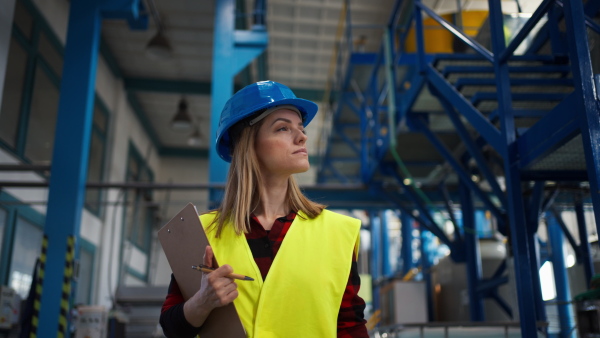 Portrait of female engineer working in industrial factory, doing control.