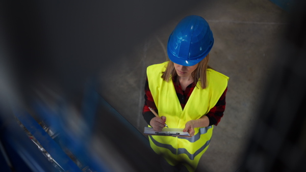 Portrait of female engineer working in industrial factory, doing control.