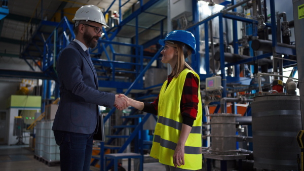 An engineering manager and mechanic worker shaking hands before doing routine check up in industrial factory