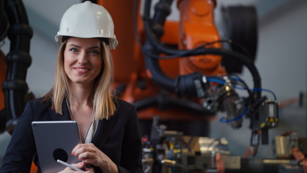 A portrait of female chief engineer in modern industrial factory using tablet.