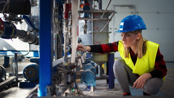 A woman worker working in industrial factory, programming machine.