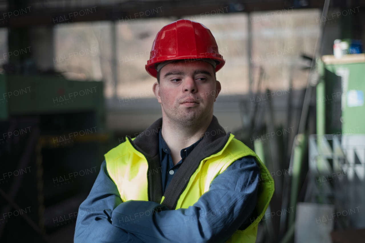 A young man with Down syndrome working in industrial factory, social integration concept.