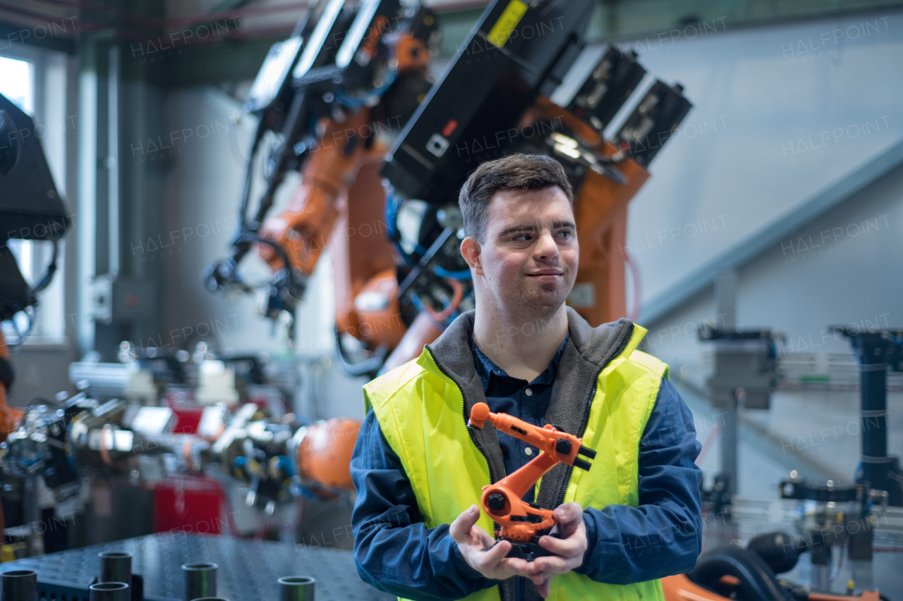 A young man with Down syndrome looking at blueprints when working in industrial factory, social integration concept.