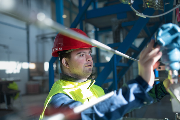 A young man with Down syndrome working in industrial factory, social integration concept.