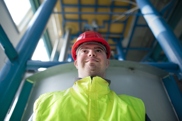 A young man with Down syndrome working in industrial factory, social integration concept.