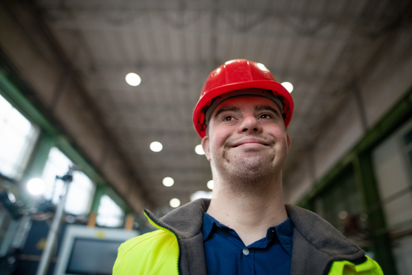 A young man with Down syndrome working in industrial factory, social integration concept.