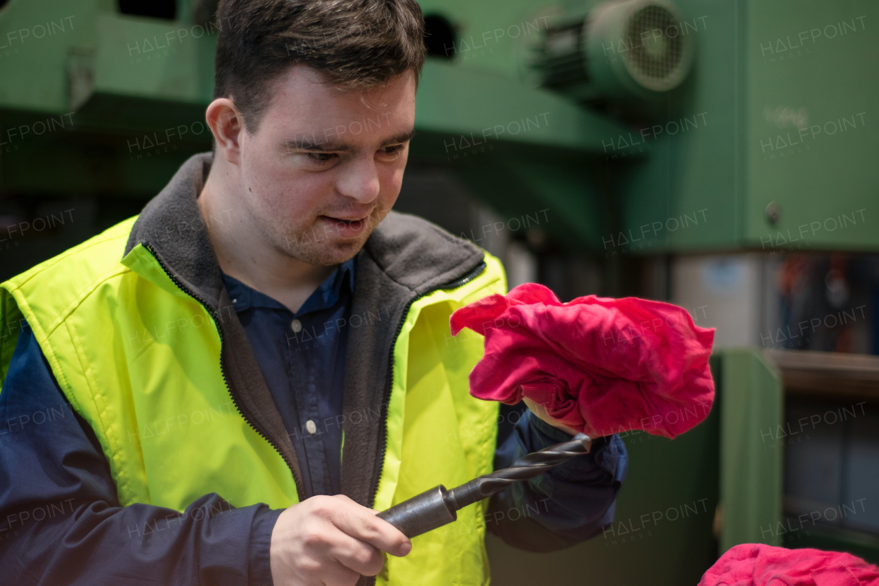 A young man with Down syndrome working in industrial factory, social integration concept.