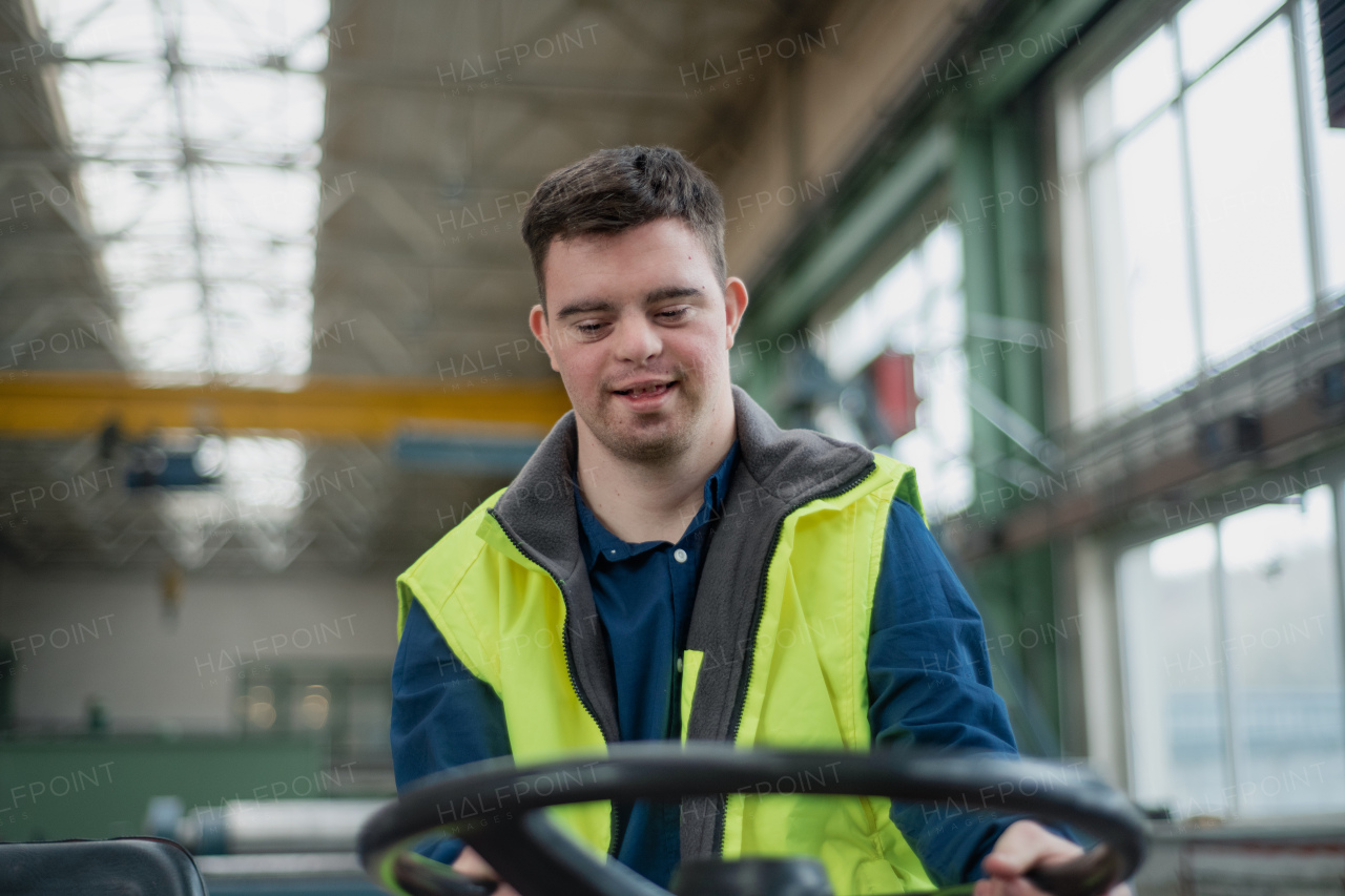 A young man with Down syndrome working in industrial factory, social integration concept.