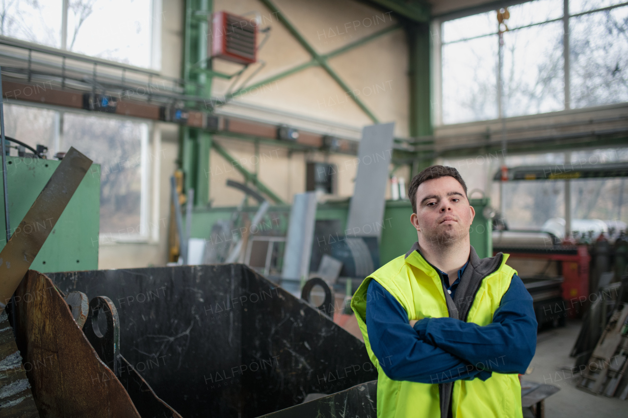 A young man with Down syndrome working in industrial factory, social integration concept.