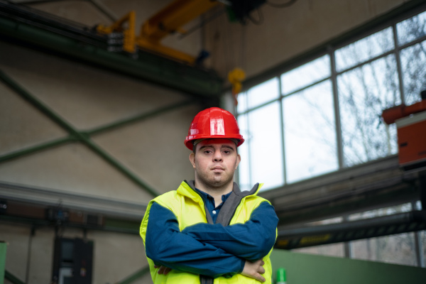 A young man with Down syndrome working in industrial factory, social integration concept.