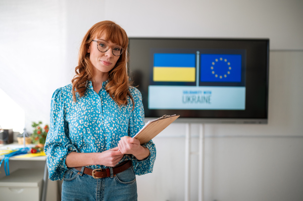 A teacher looking at camera in classroom, concept of enrolling Ukrainian kids to schools.