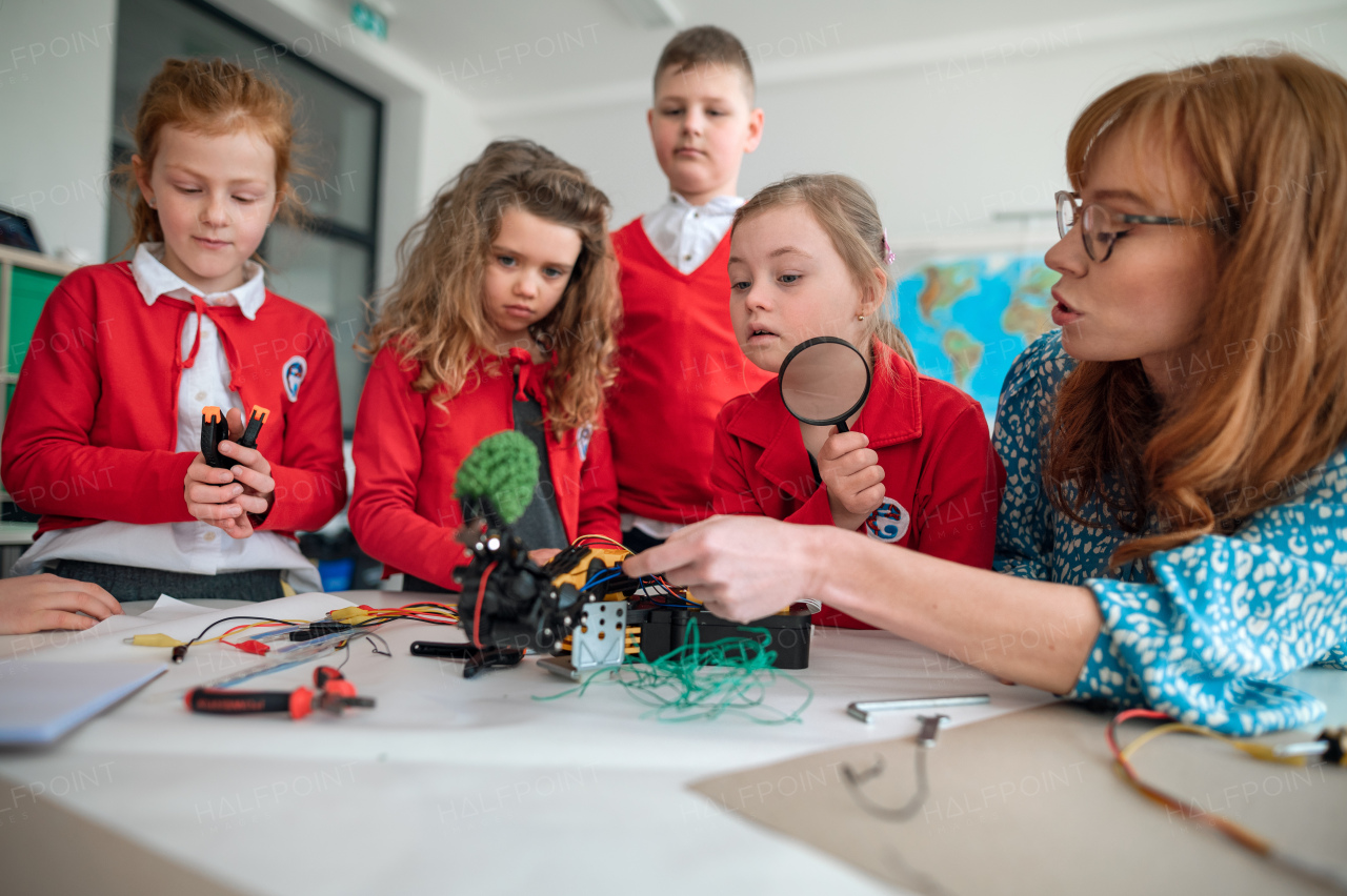 A group of kids with their teacher programming electric toys and robots at robotics classroom