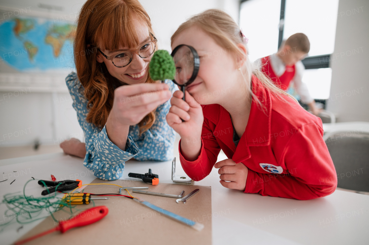 A little student with Down syndrome with tutor teacher programming electric toys and robots at robotics classroom