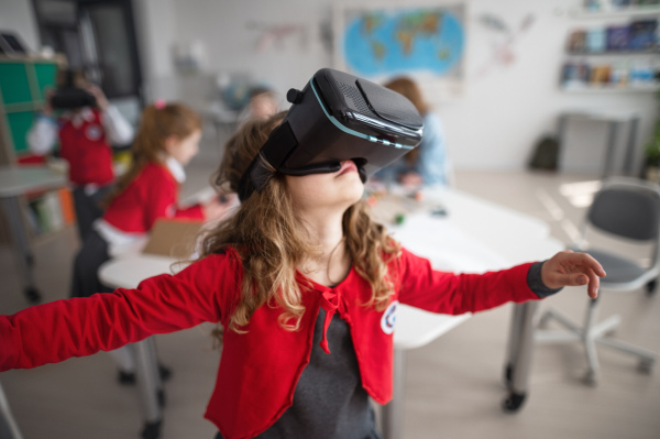 A happy schoolgirl wearing virtual reality goggles at school in computer science class