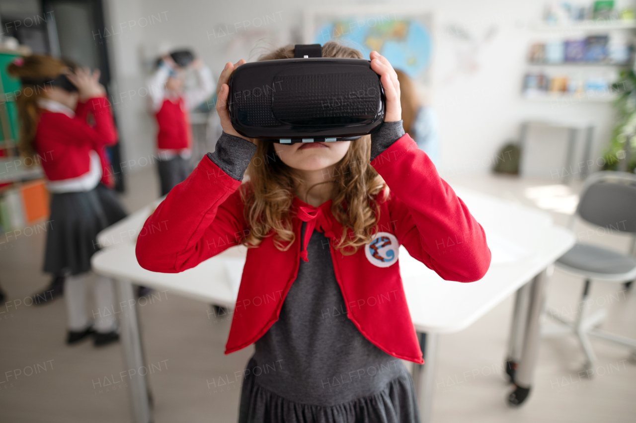 A happy schoolgirl wearing virtual reality goggles at school in computer science class