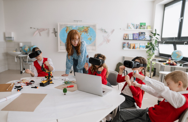 Happy schoolchildren wearing a virtual reality goggles at school in computer science class