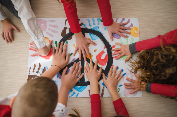 A top view of children making a poster of peace sign at school.