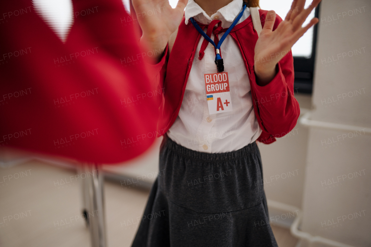 A schoolgirl with blood type sticker at school, Ukrainian war concept.