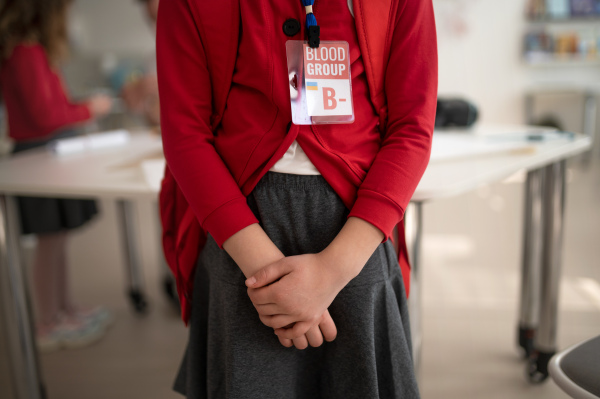 A schoolgirl with blood type sticker at school, Ukrainian war concept.