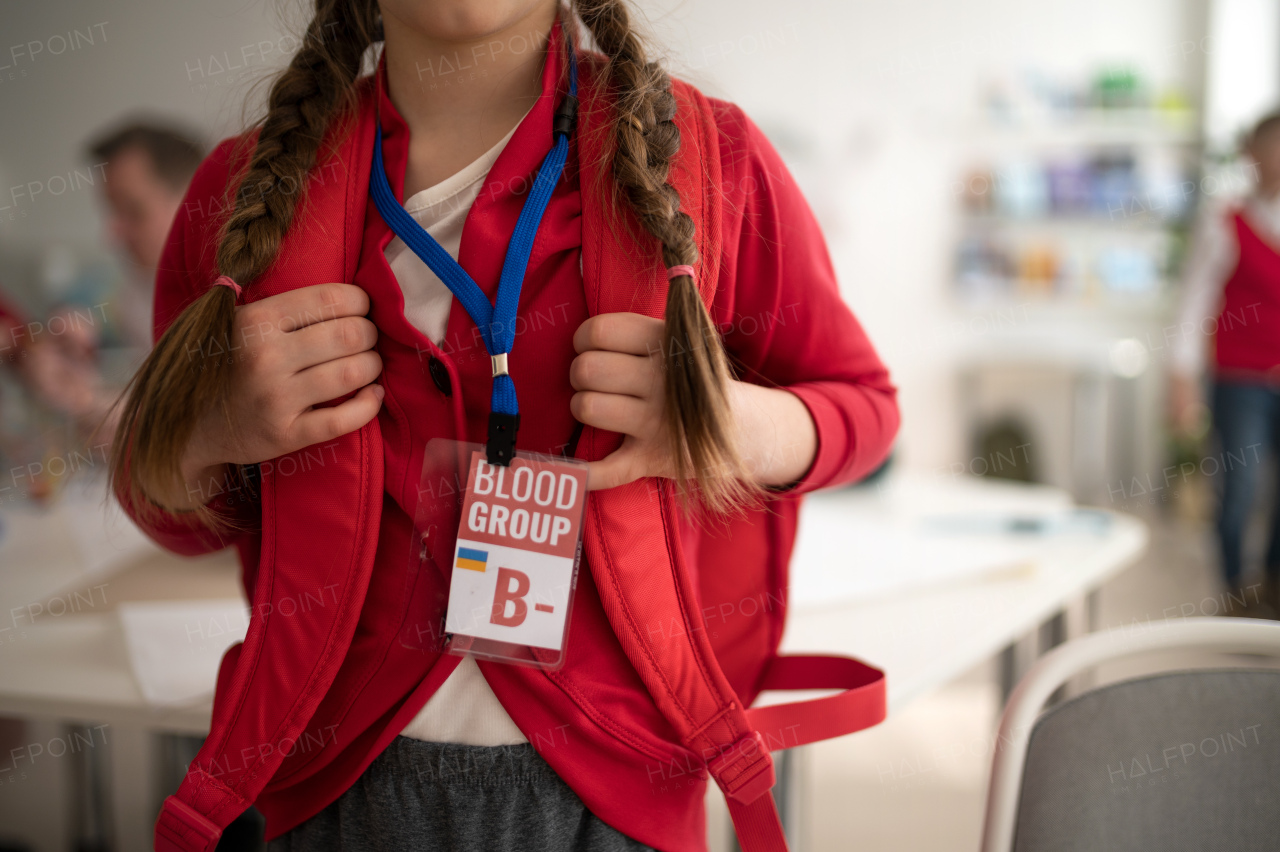 A schoolgirl with blood type sticker at school, Ukrainian war concept.