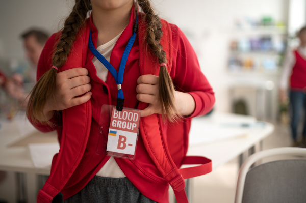 A schoolgirl with blood type sticker at school, Ukrainian war concept.