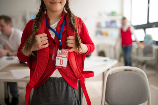 A schoolgirl with blood type sticker at school, Ukrainian war concept.