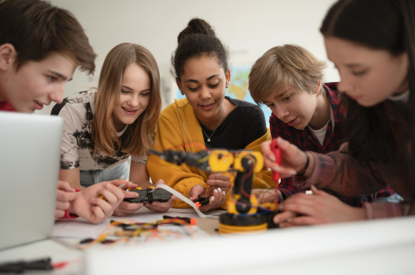 A group of students building and programming electric toys and robots at robotics classroom