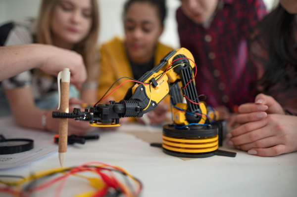 A group of students building and programming electric toys and robots at robotics classroom