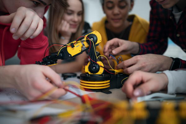 A group of students building and programming electric toys and robots at robotics classroom