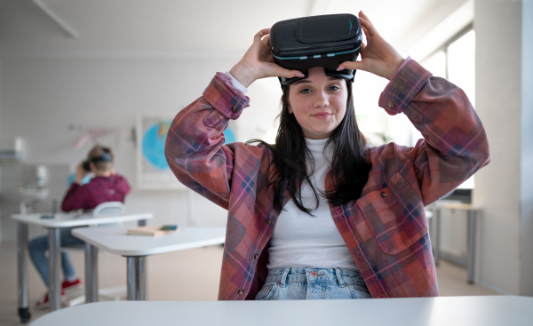 A happy student wearing virtual reality goggles at school in computer science class