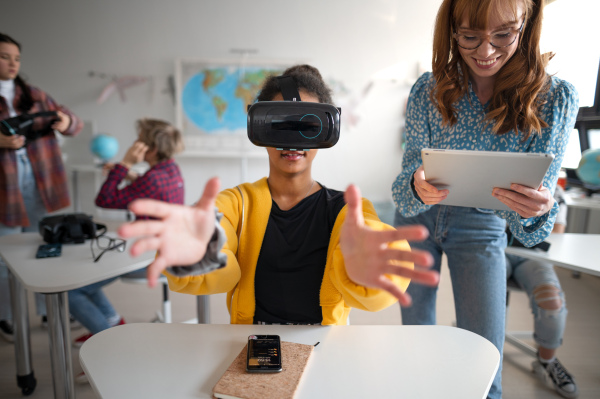 Teenage students wearing virtual reality goggles at school in a computer science class