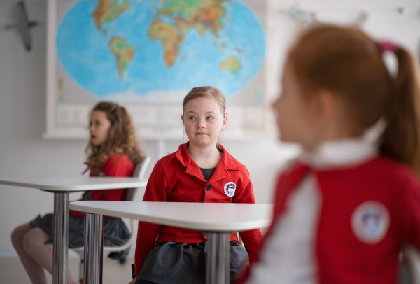 A down syndrome schoolgirl paing attention in class at school, integration concept.