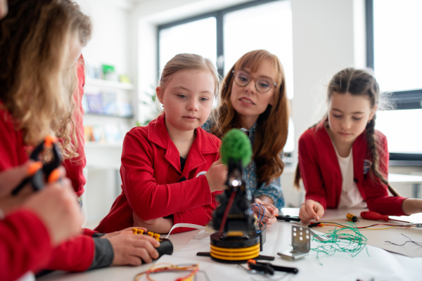 A group of kids with their teacher programming electric toys and robots at robotics classroom