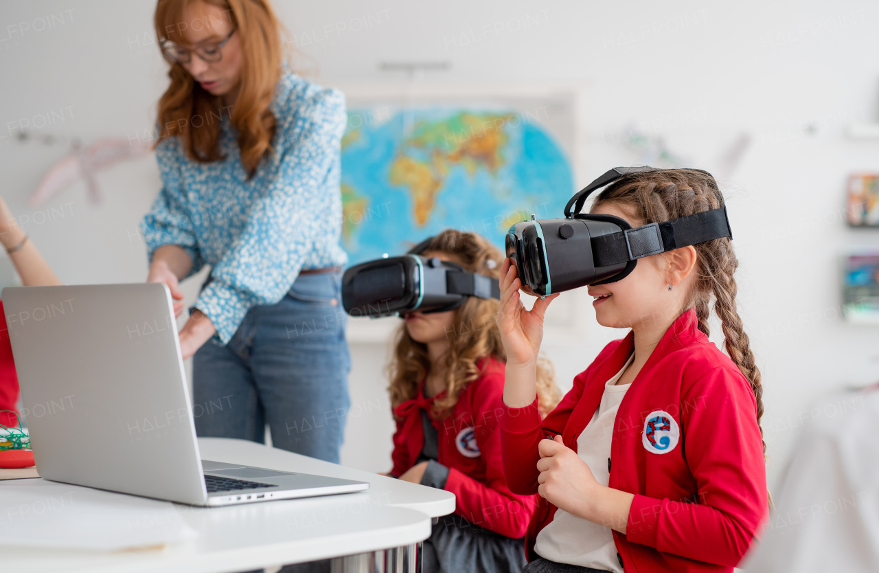 Happy schoolchildren wearing a virtual reality goggles at school in computer science class