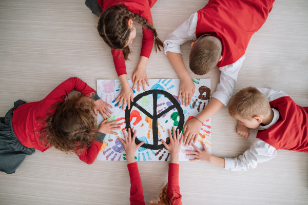 A top view of children making a poster of peace sign at school.