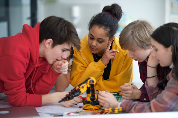 A group of students building and programming electric toys and robots at robotics classroom