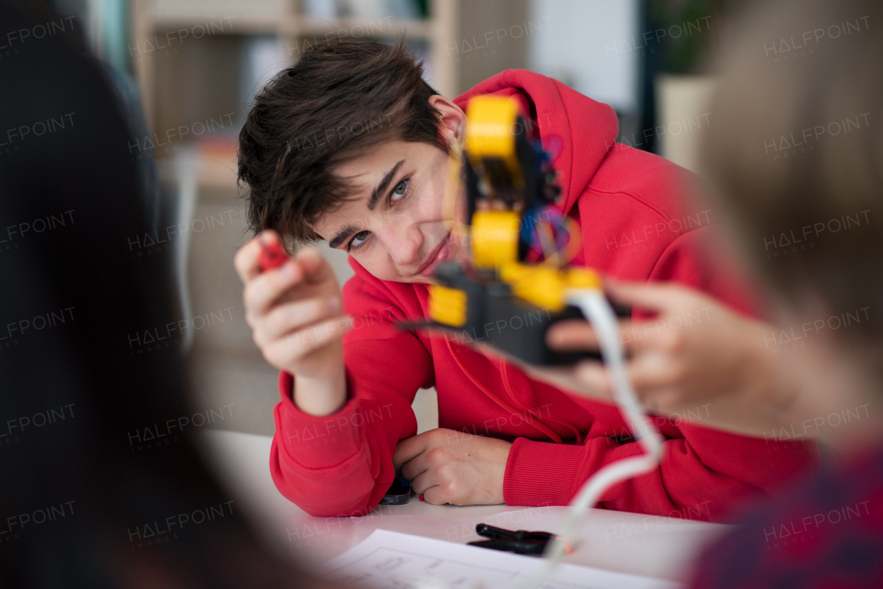 A group of students building and programming electric toys and robots at robotics classroom