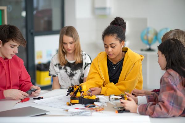 A group of students building and programming electric toys and robots at robotics classroom