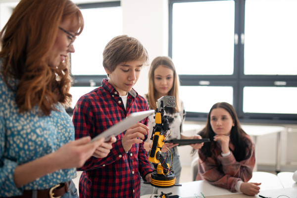 A college student presenting his builded robotic toy to young science teacher at robotics classroom at school.