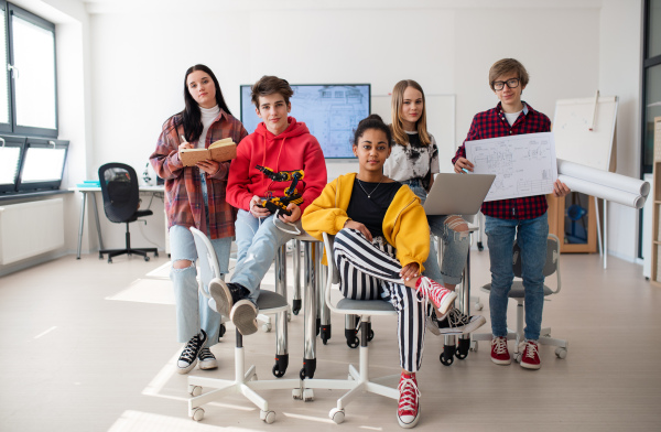 Group of students sitting and posing together in a robotics classroom