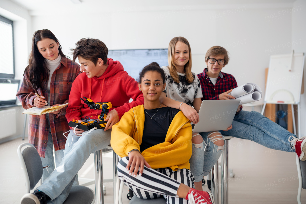 Group of students sitting and posing together in a robotics classroom