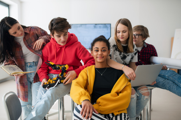 Group of students sitting and posing together in a robotics classroom