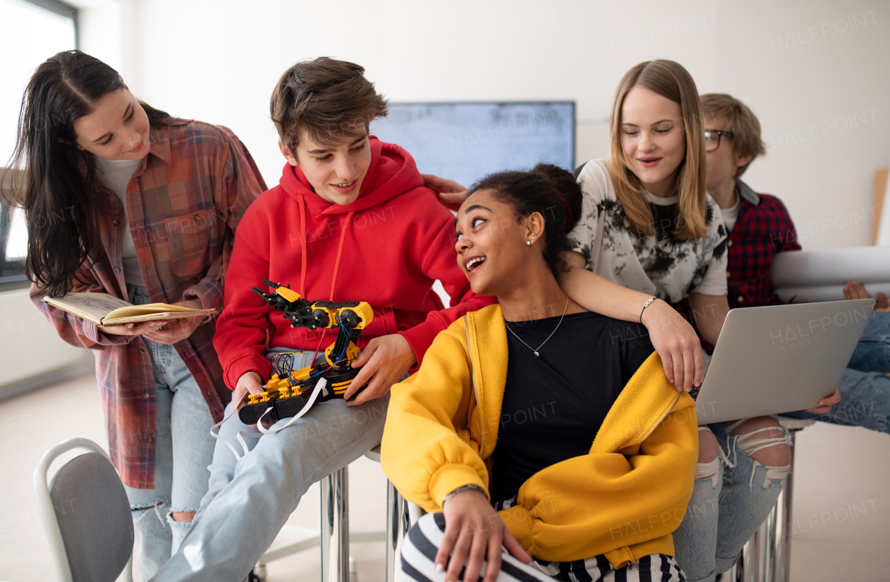 Group of students sitting and posing together in a robotics classroom