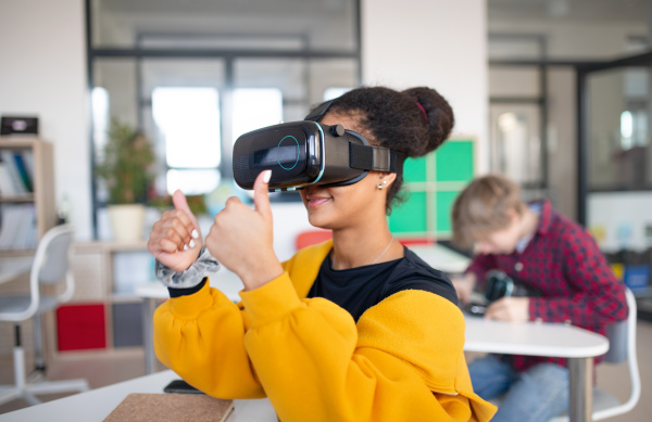 A happy student wearing virtual reality goggles at school in computer science class