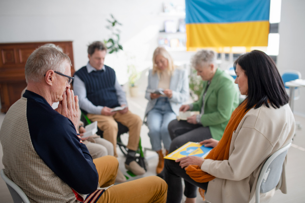 A group of seniors praying for Ukraine together in church community center.