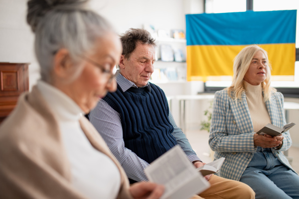 A group of seniors praying for Ukraine together in church community center.