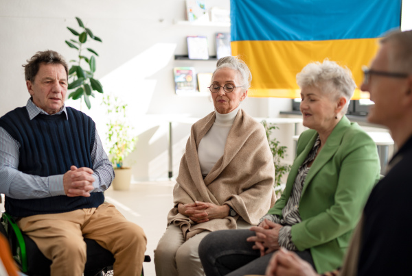 A group of seniors praying for Ukraine together in church community center.