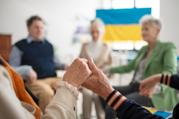 A group of seniors praying for Ukraine together in church community center.