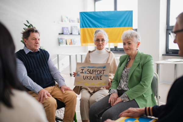 A group of seniors showing support when praying for Ukraine together in church community center.